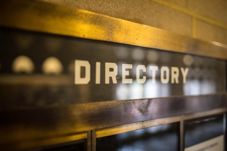 Closeup of the word "directory" on a glass covered bulletin board that's affixed to a wall
