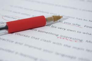 Photo of a red pen laying on a corrected/marked-up document