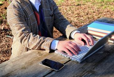 Person typing on laptop while outside