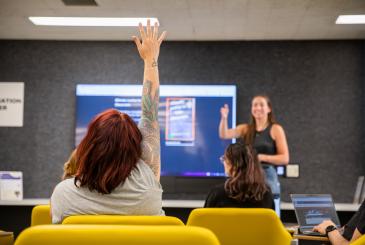 A person raises their hand and an instructor points to them