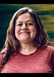 Medium length portrait of Silvia with a dark green and yellow background.